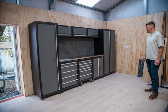Man standing in a garage with large black storage cabinets.