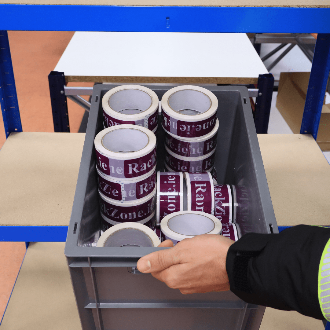 A hand holds a RackZone Euro Container 400x300x290 grey filled with packing tape.