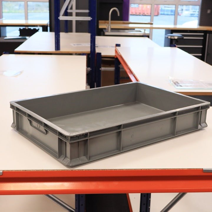 A RackZone Euro Container 600x400x100mm Grey is on a white table in a workshop.