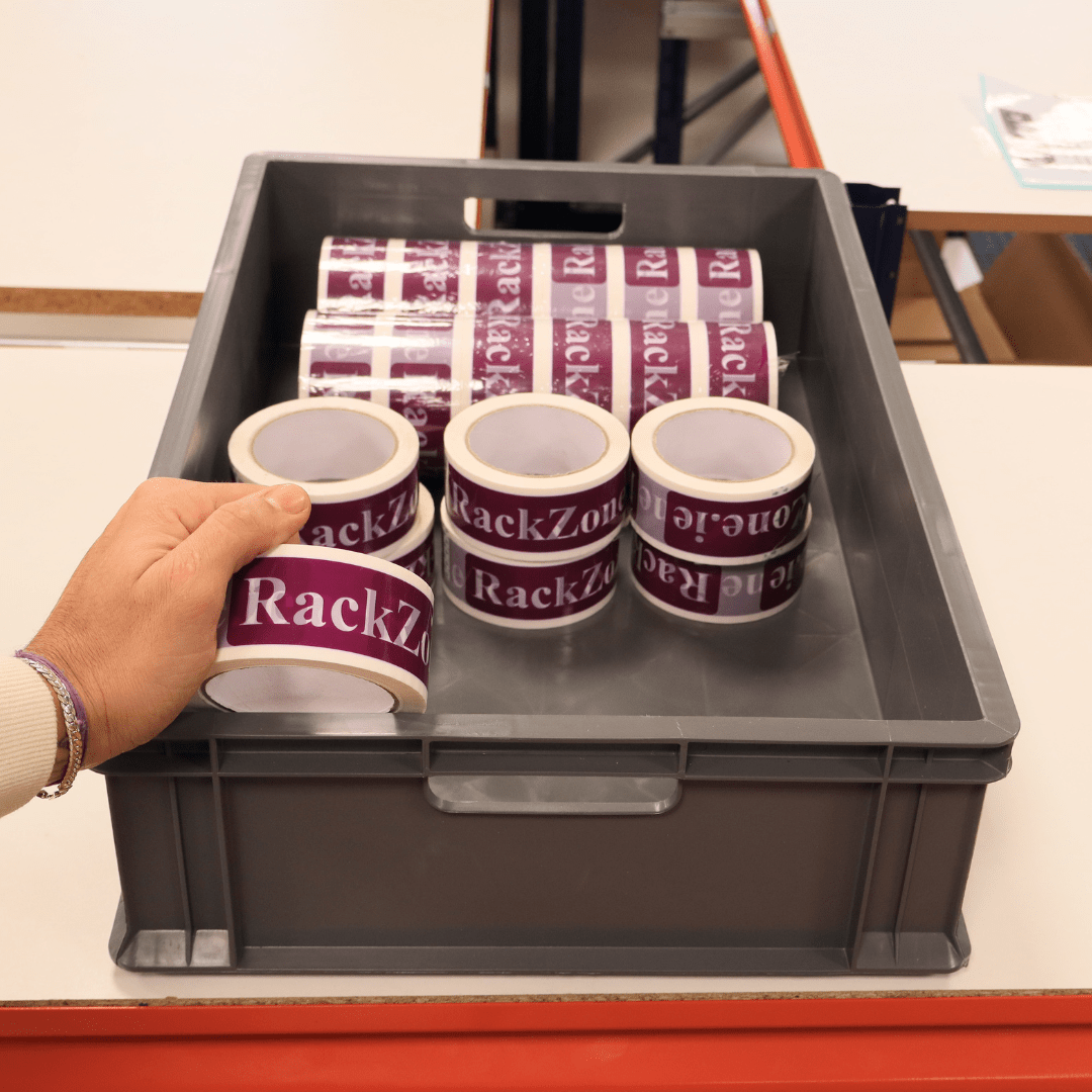 A hand holds RackZone tape above Euro Container 600x400x150mm Grey crates.