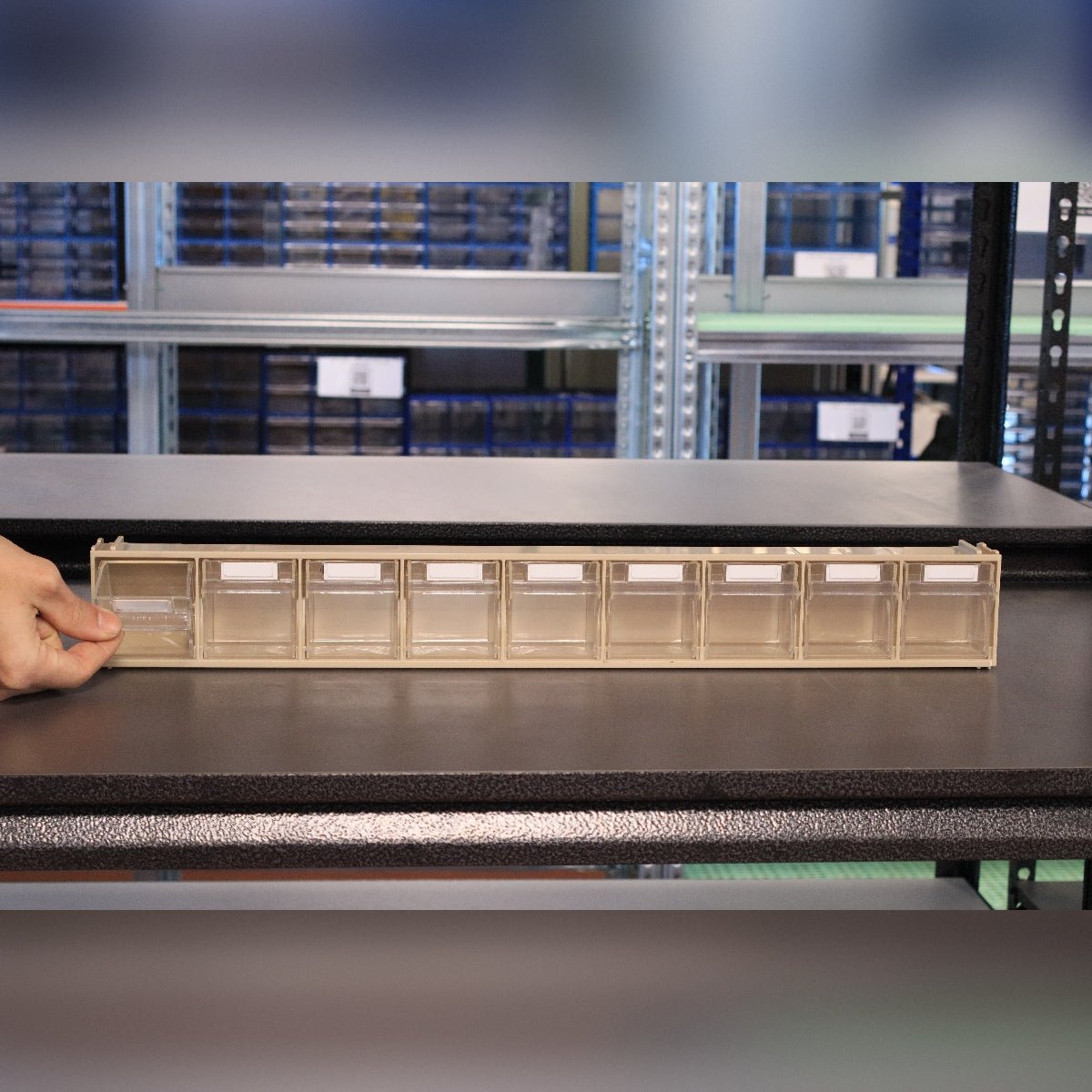 A hand holds a RackZone Storage Tilt Bin Madia 1 (9-Tilt Bin) on a shelf.