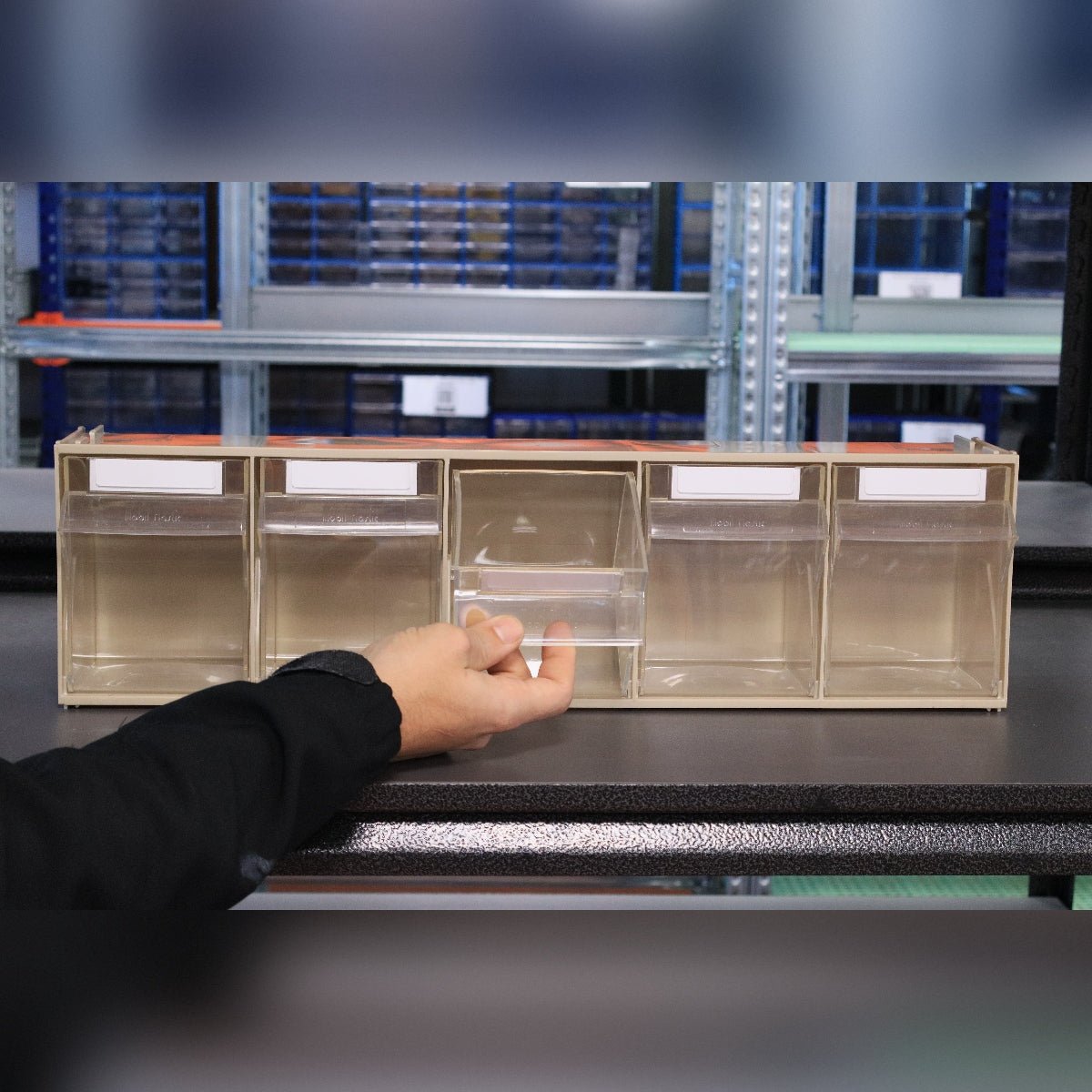 A hand pulls out a bin from the RackZone Storage Tilt Bin Madia 3 (5-Tilt Bin).