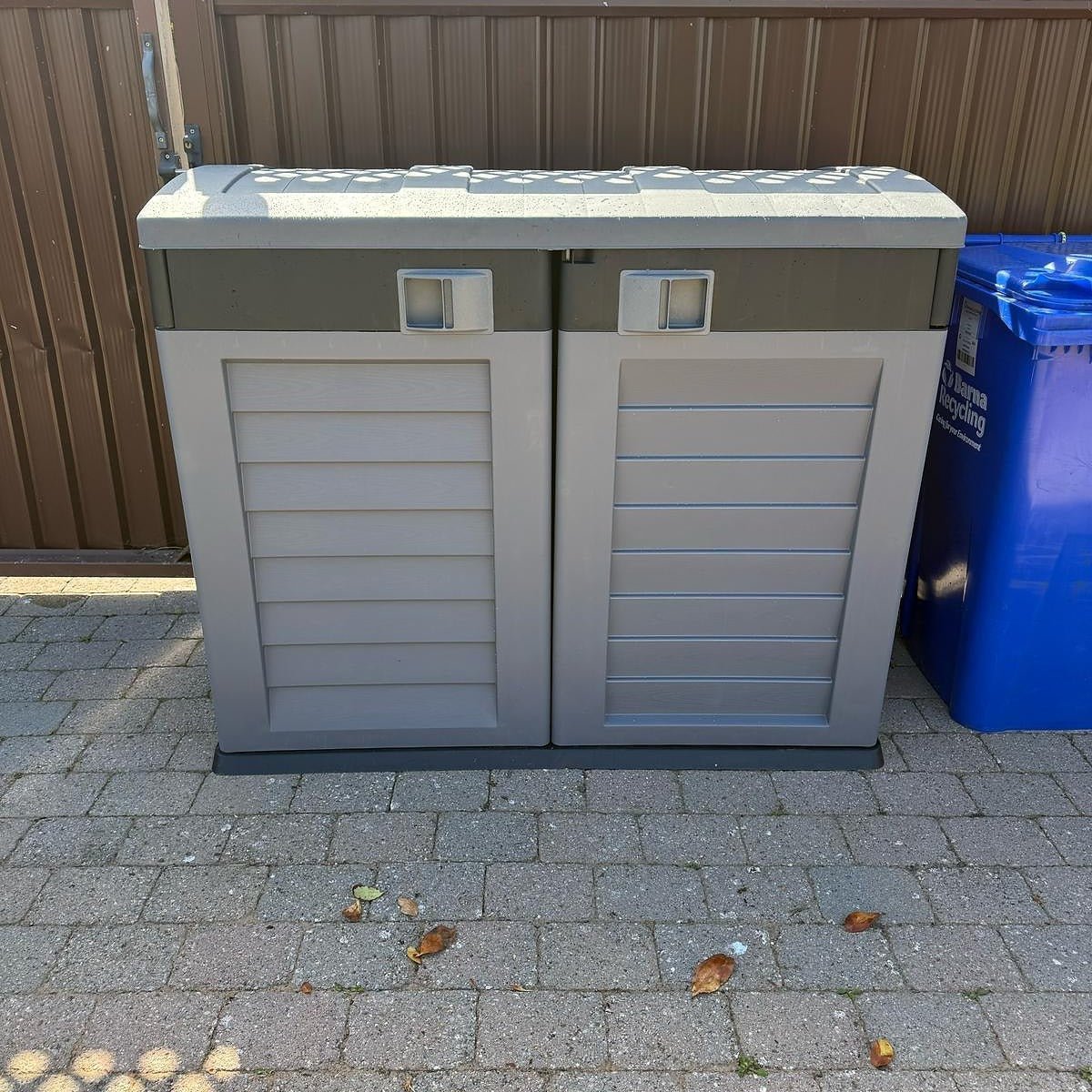 A RackZone Plastic Wheelie Bin Storage stands beside a blue recycling bin.