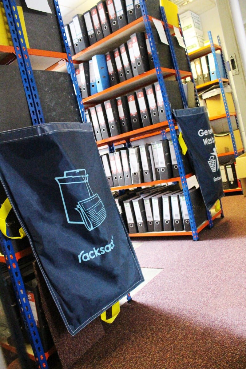Shelves of binders with two RackZone Racksack Mini Mixed Paper bins in blue.