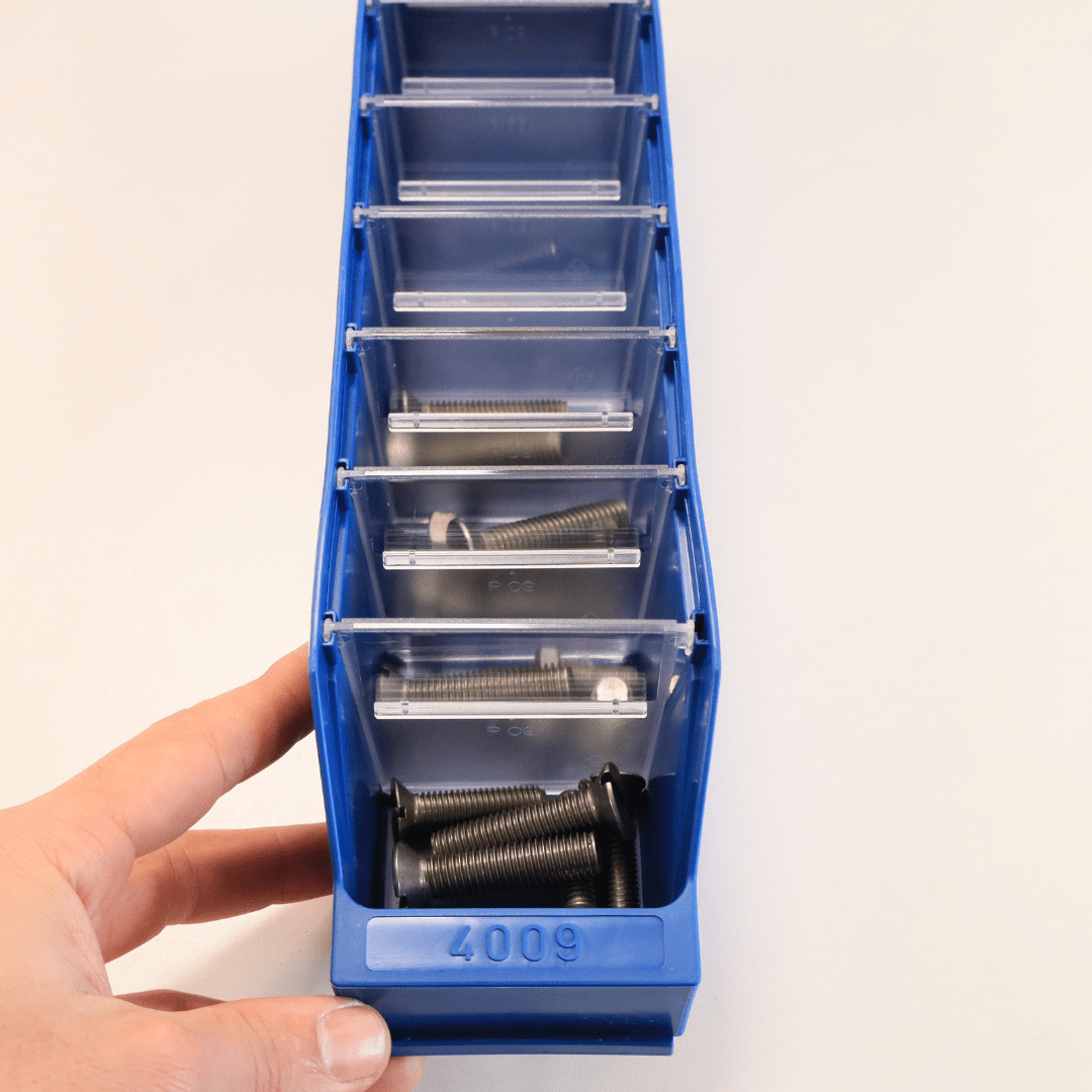 A hand holds a RackZone Standard Shelf Bin ST4009 with metal bolts inside.