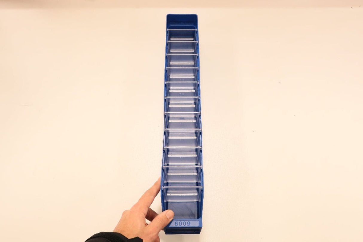 A hand points at a blue RackZone ST6009 shelf bin, seen from above.