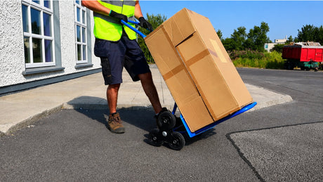 A blue metal hand truck with two black wheels and red handles, positioned upright on a white background.