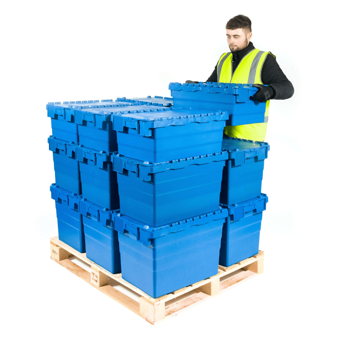 A person wearing a yellow safety vest organizes blue plastic storage crates stacked on a wooden pallet.