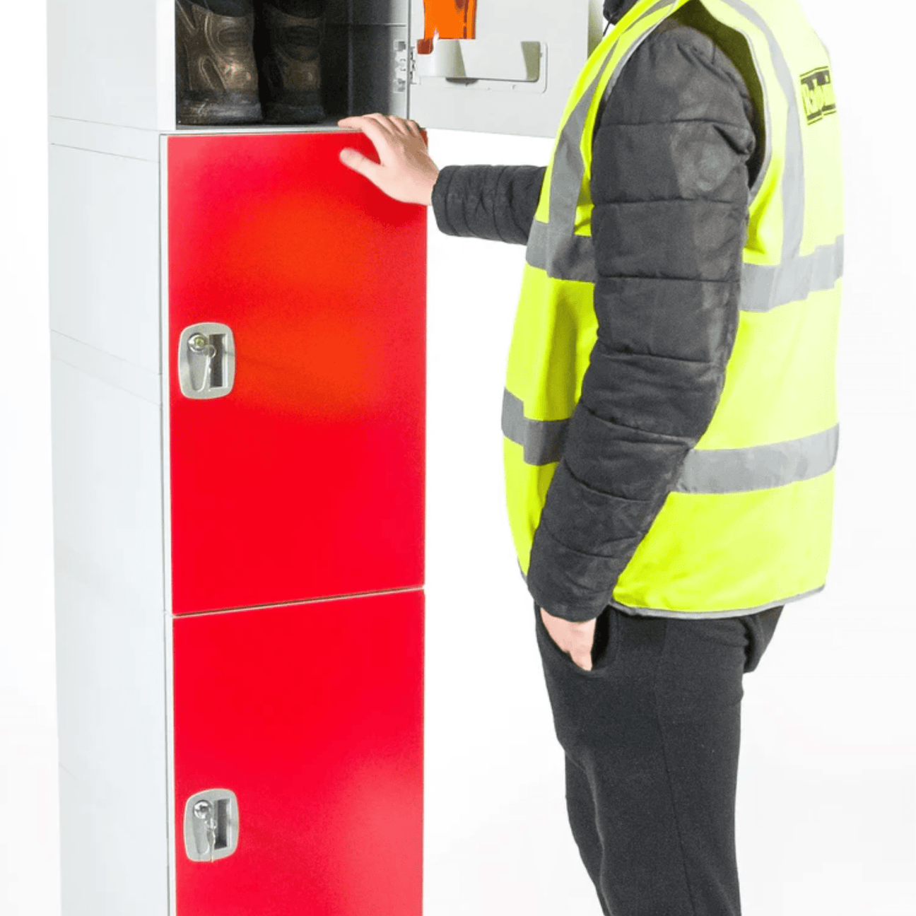 Person in a yellow safety vest standing beside a red and white locker unit, with one hand on an open upper locker containing boots.