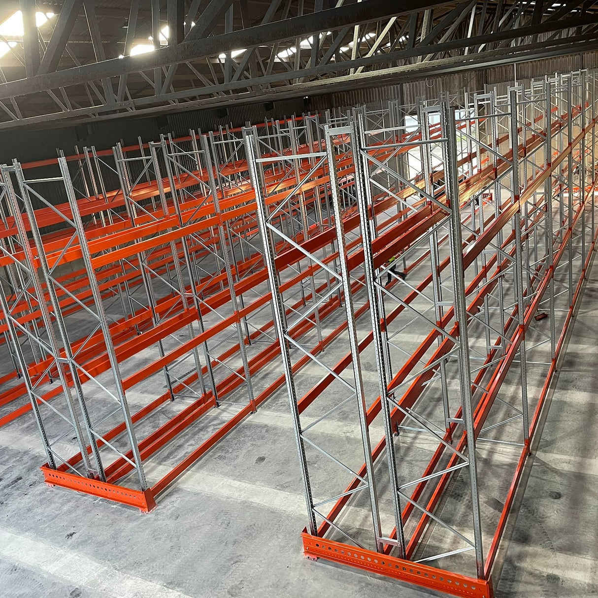 Pallet rack system in a warehouse setting with concrete flooring and metal beams.