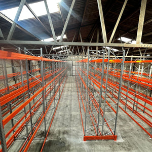 Warehouse interior with orange pallet racks and concrete floor.