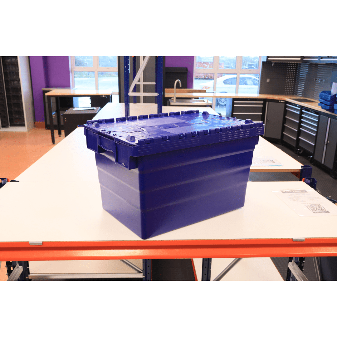 A RackZone 66L blue attached lid container sits on a white table in a workshop.