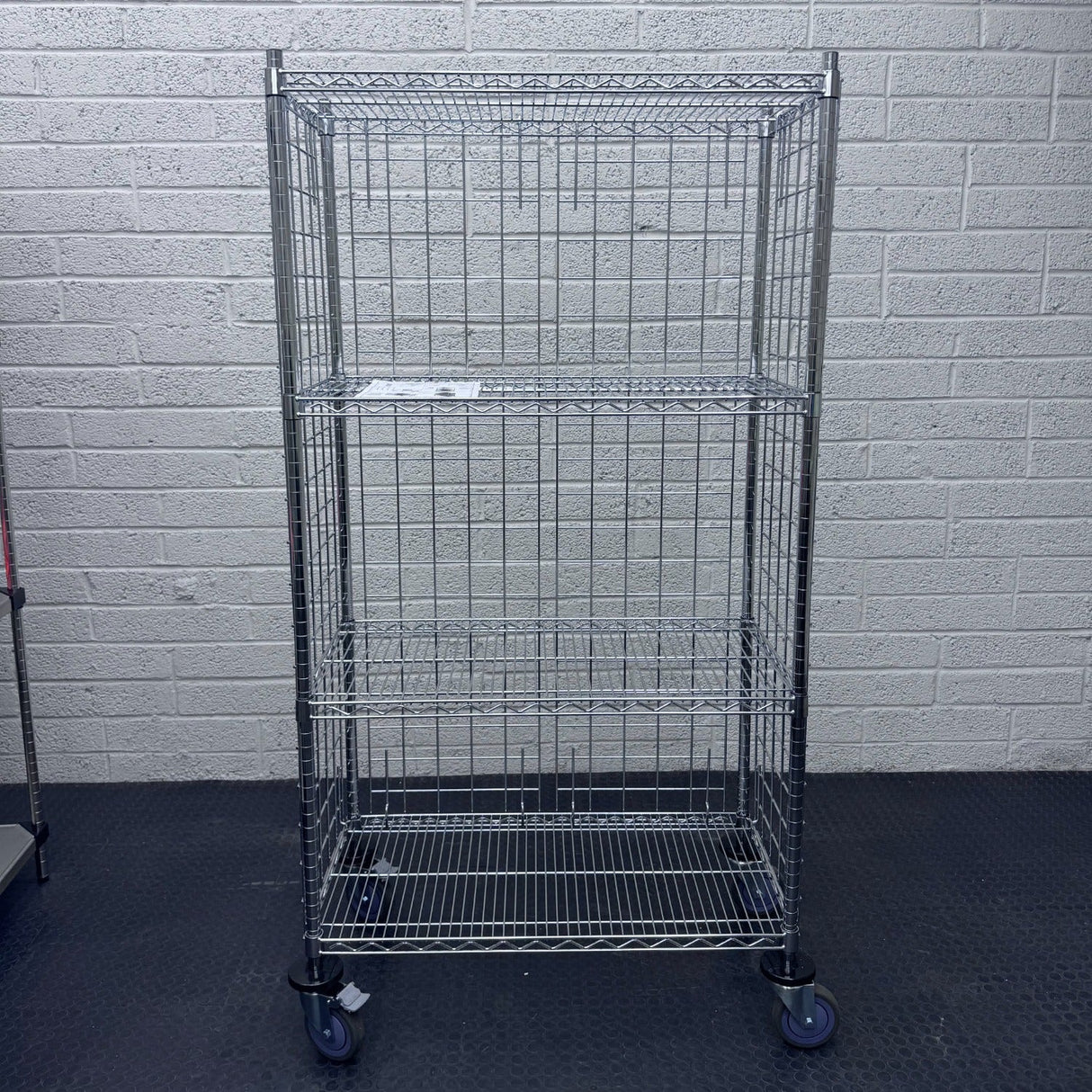 A RackZone 4 Tier Chrome Trolley on wheels stands on a black floor.