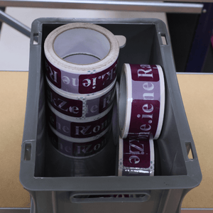 A RackZone Euro Container holds rolls of purple and white printed tape.