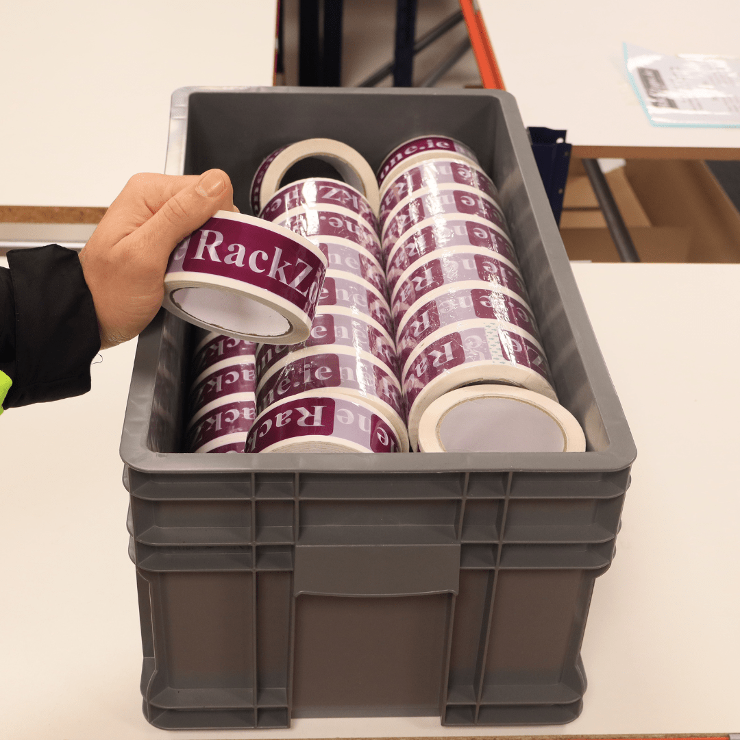 A hand holds tape above RackZone Euro Container 505x295x235 Grey bins.