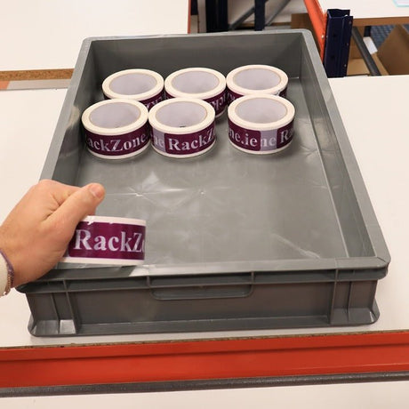 A hand holds tape by RackZone Euro Container 600x400x100mm Grey storage boxes.