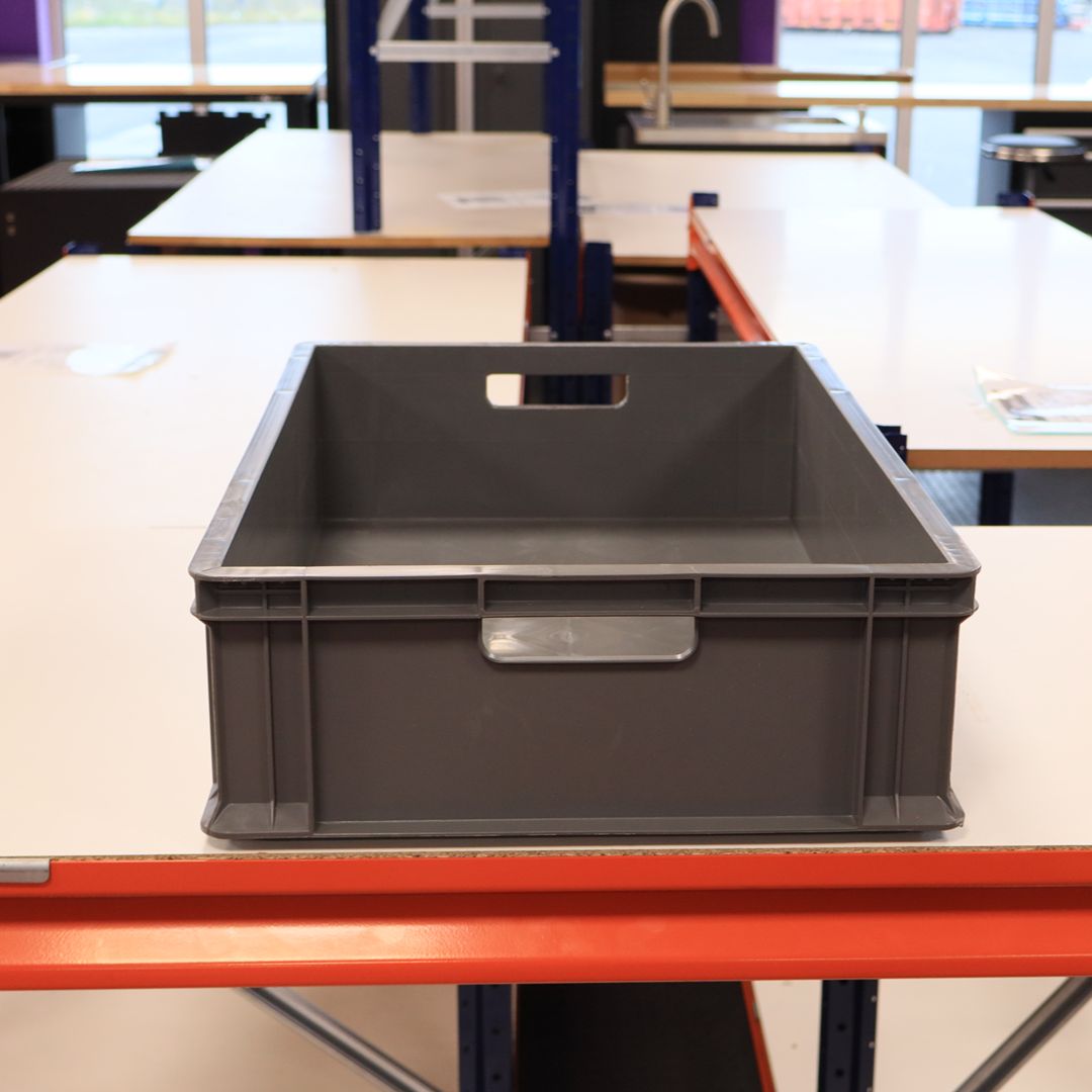 A RackZone grey Euro container sits on a white table in a workspace.