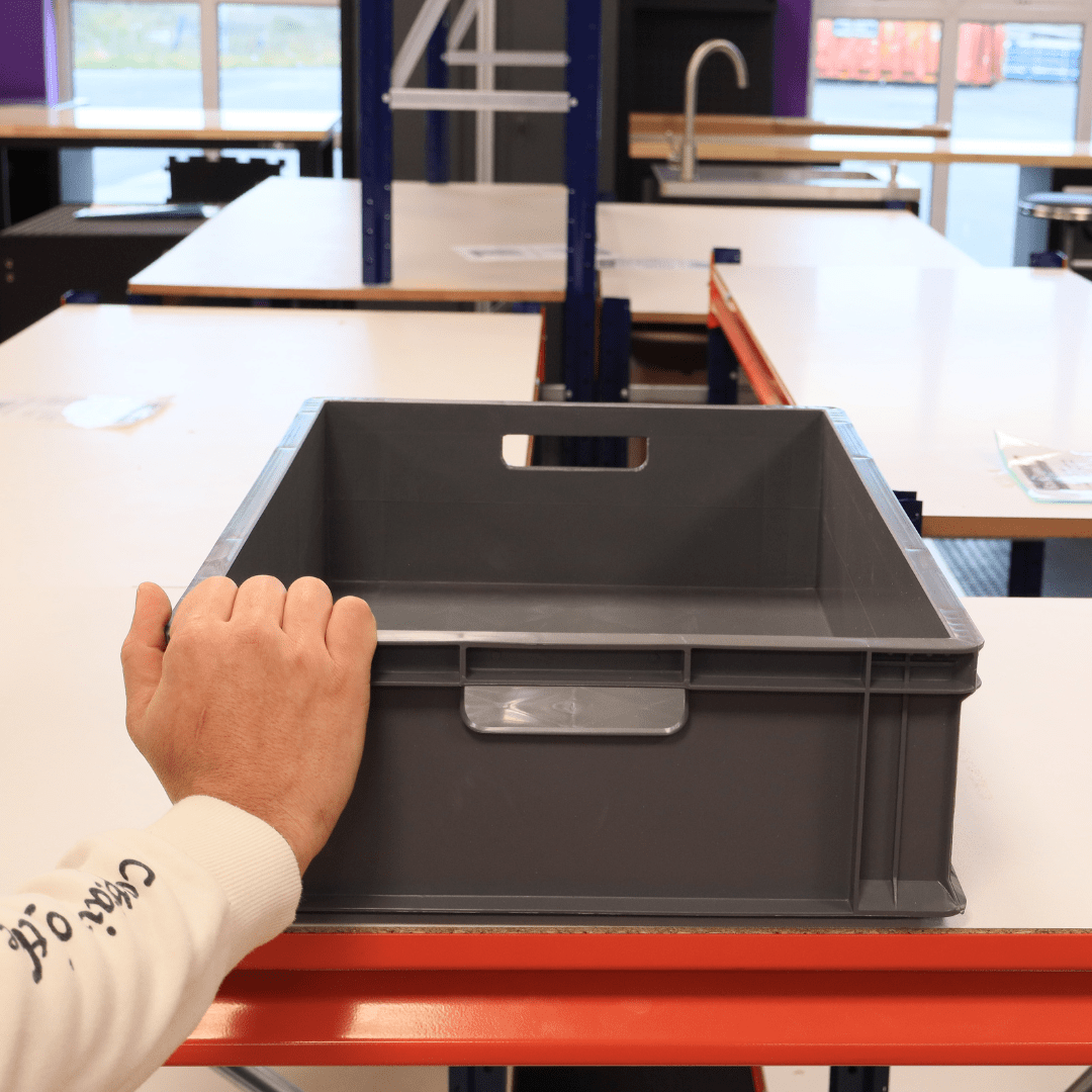 A person moves RackZone Euro Containers 600x400x150mm grey on a table.