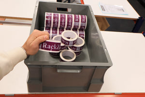 A hand picks up a grey RackZone Euro Container from industrial storage.