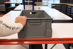 A person places a RackZone 600x400x230mm Euro Container on a white table.