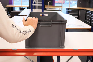 A person holds a RackZone 600x400x280mm Grey Euro Container in a workshop.