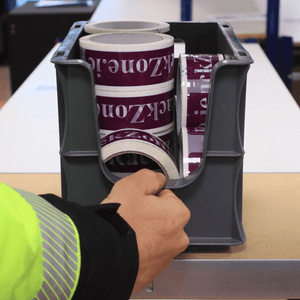 Someone grabs a Euro Picking Container by RackZone near packing tape.