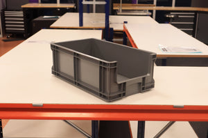 A RackZone grey Euro Picking Container is on a white worktable in a workshop.