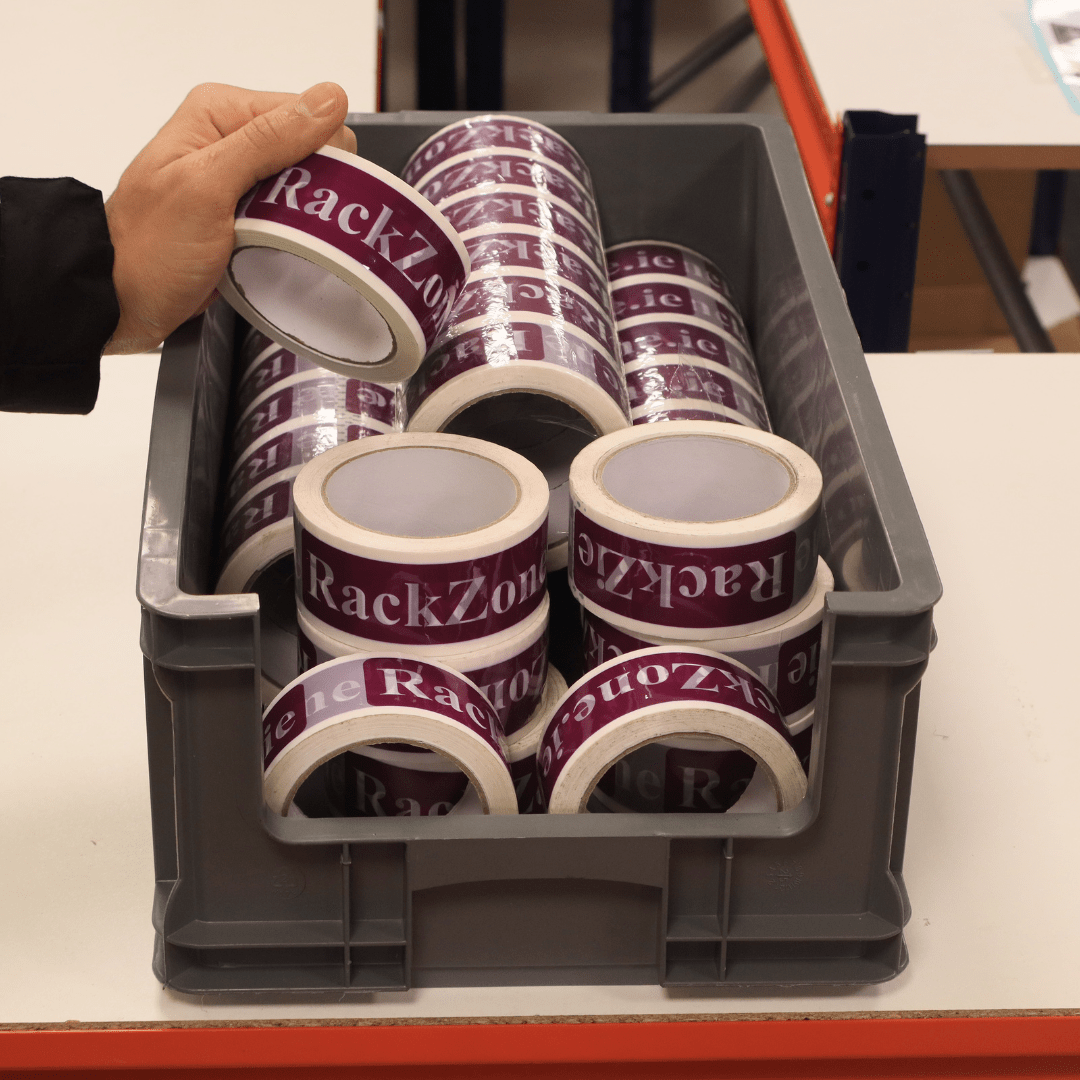 A hand holds "RackZone" Euro Picking Container above a box of storage bins.