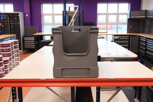 A RackZone grey Euro Picking Container sits on a white workbench in a workshop.