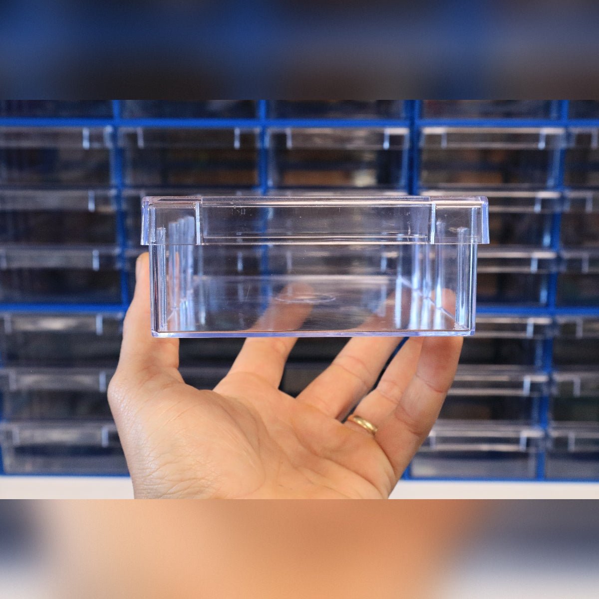 A hand holds a RackZone Plastic Drawer 108 Box, blue, for small parts storage.