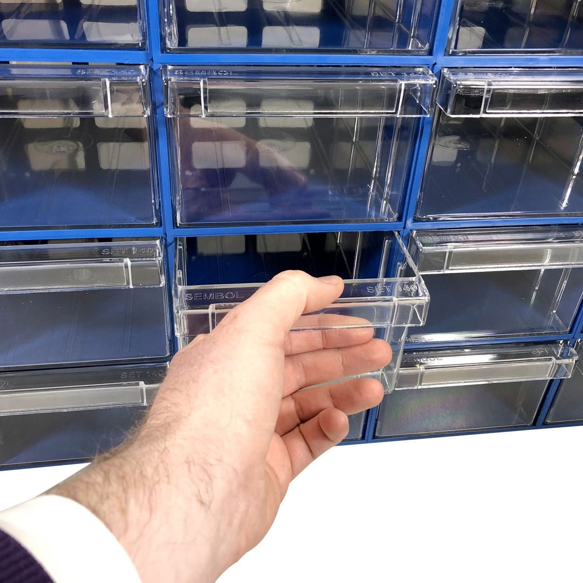 A hand pulls out a clear drawer from the RackZone 32-box blue organizer.
