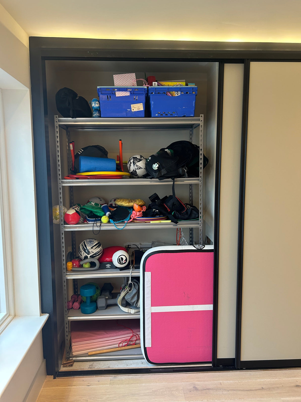 RackZone Rivet Shelving holds sports gear, toys, and a pink exercise mat.