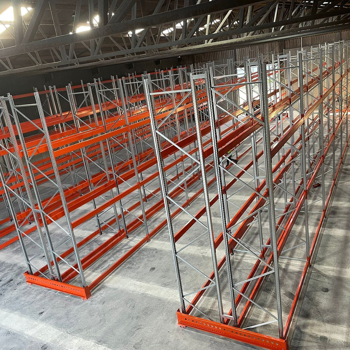 Pallet rack system in a warehouse setting with concrete flooring and metal beams.