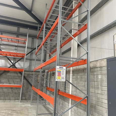 Metal shelving units with orange shelves in a warehouse setting.