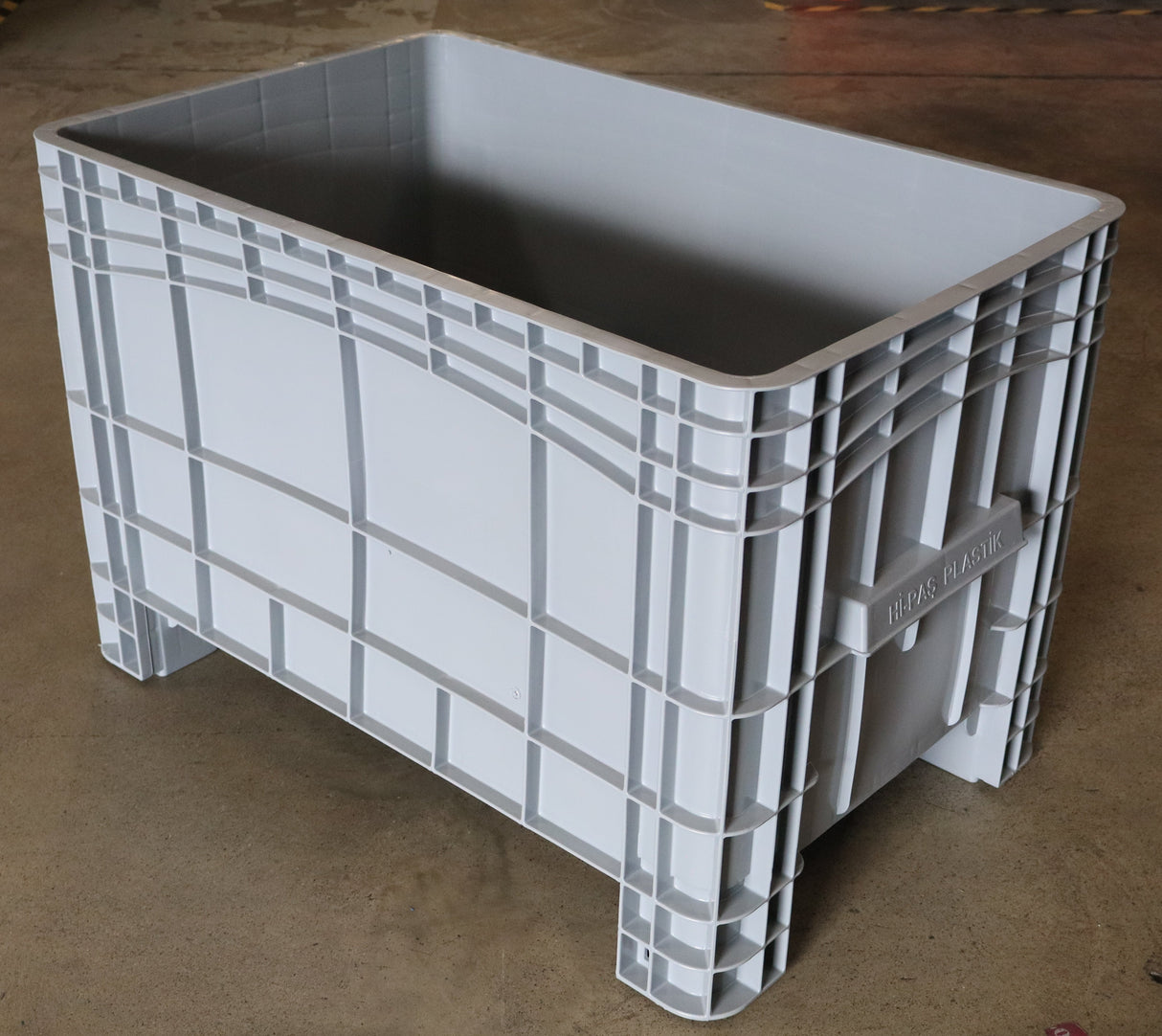 A large RackZone Stacking Container 984x625x665mm Grey on a concrete floor.