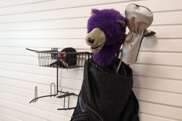 The RackZone Slatwall Golf Rack stores clubs with purple bear, silver headcovers.