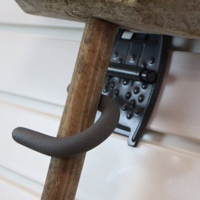 The RackZone Slatwall Grip Hook holds a wooden handle for shed organization.