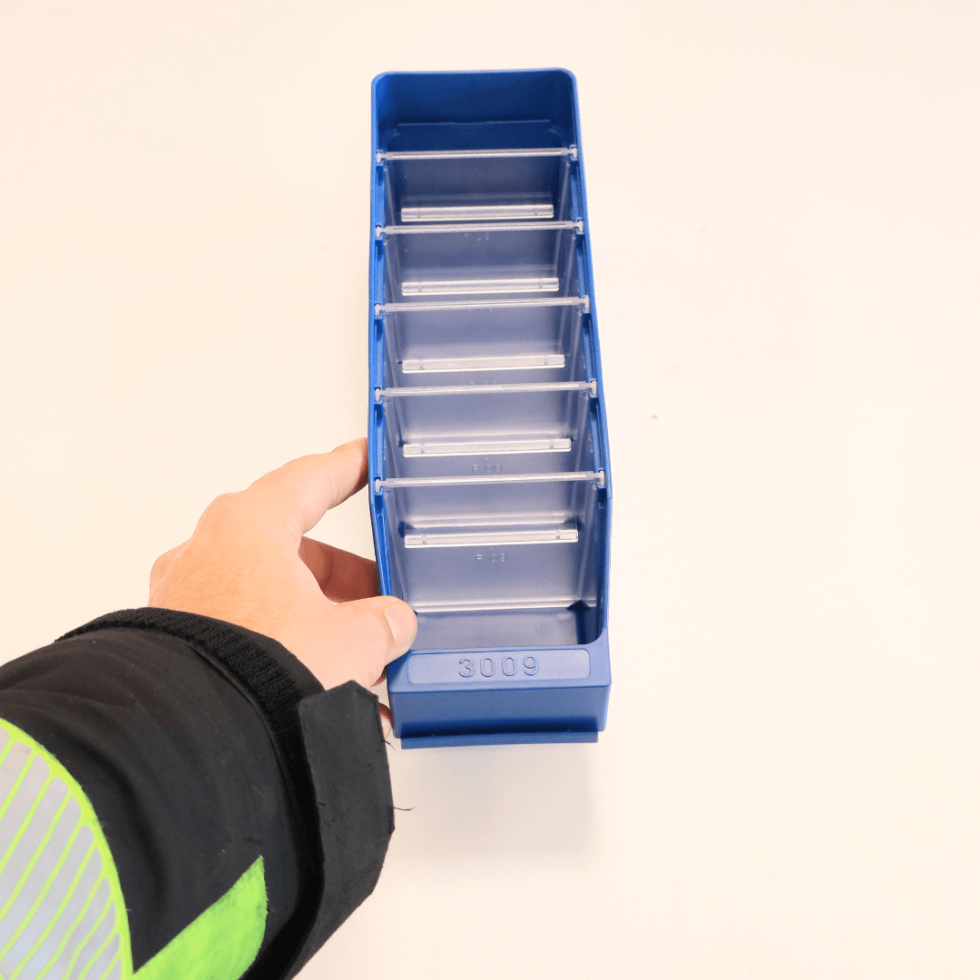 A hand holds a RackZone Standard Shelf Bin ST3009 blue, 300x90x95mm, with dividers.