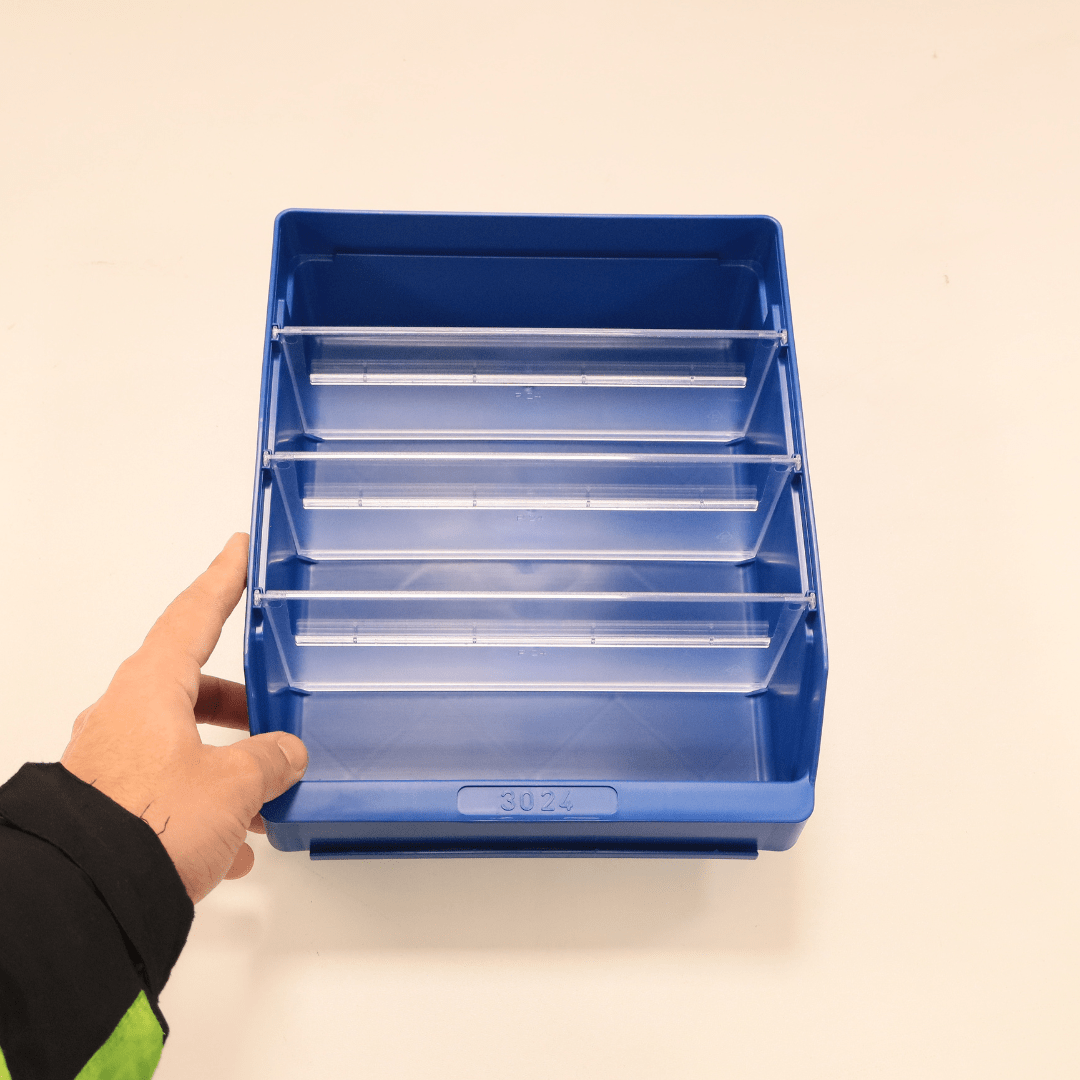 A hand holds a RackZone ST3024 blue shelf bin with four clear dividers.