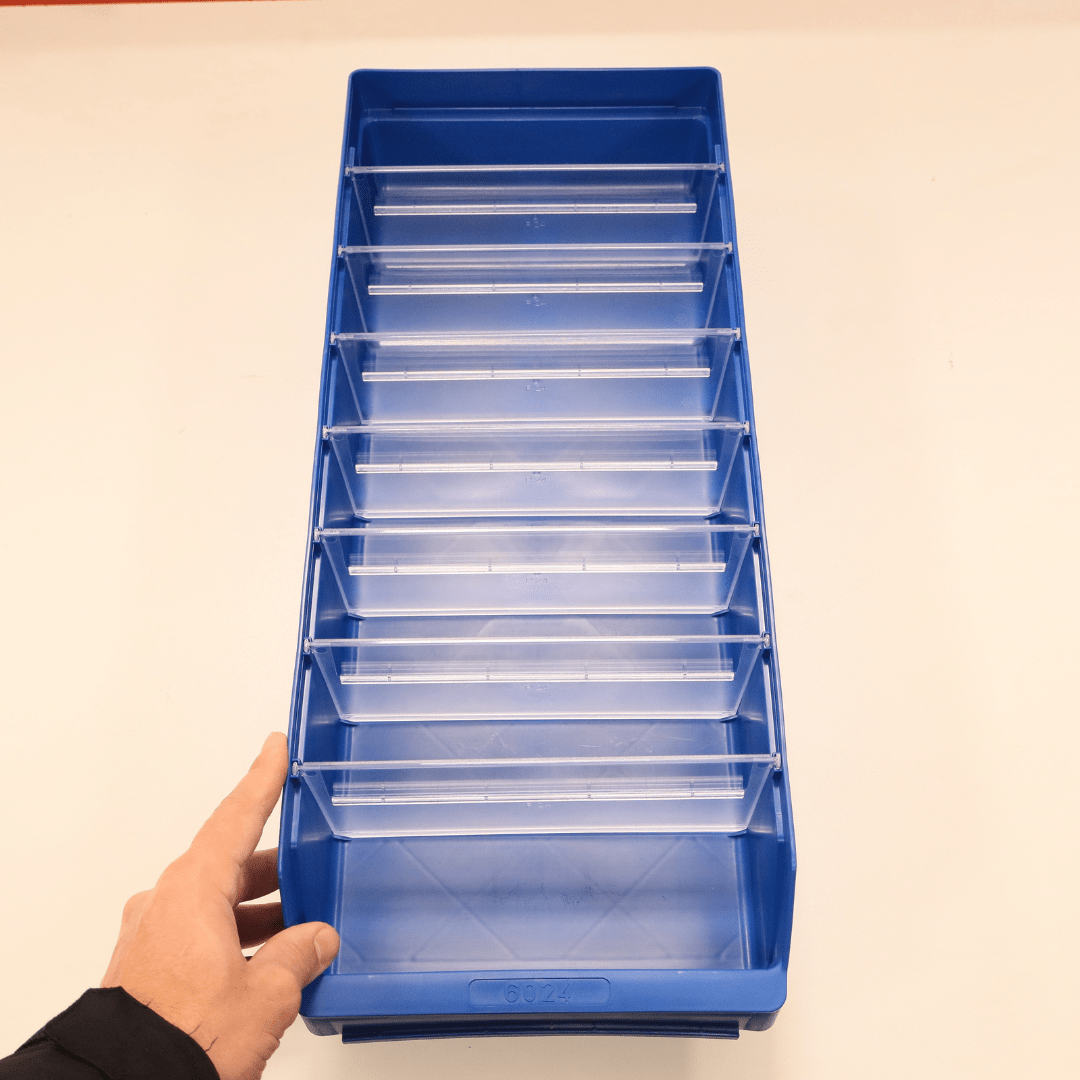 A hand holds a RackZone Standard Shelf Bin ST6024, blue with clear dividers.