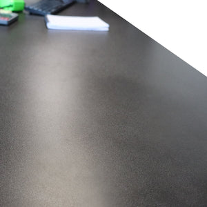 A RackZone L-Shaped Sit-Stand Desk with office supplies and papers in back.